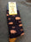 A pair of dark navy crew socks with a pinkish-brown pig pattern and mustard yellow heels, shown with a yellow 'Doris & Dude' brand tag.